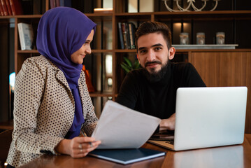 Fototapeta na wymiar A young Muslim bussines woman and man working together in the office.