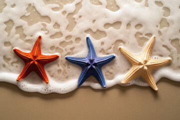 Fototapeta na wymiar Three different color starfishes on the wave s sand background