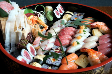 Selection of traditional sushi and sashimi on a black plate