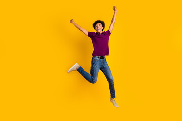 Full length photo of overjoyed glad man wear trendy violet clothes jump up raise hands fist scream yes isolated on yellow color background