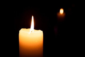 lit candle in the dark and its reflection in the background