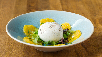 Burrata grapefruit salad in a dish on a wooden table in a restaurant