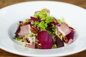 Roast beef and beetroot salad with pecan nuts in white bowl