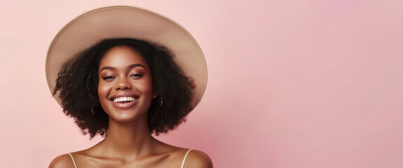 Portrait of a joyful young woman wearing a stylish hat with natural curly hair on a pastel pink background, expressing happiness with a bright smile.