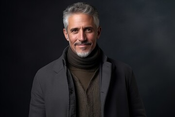 Portrait of a handsome mature man with grey beard and mustache wearing a woolen sweater and scarf.