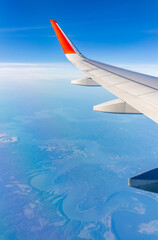 Aerial view from airplane window above green ground. View from the airplane window with beautiful clouds at sunrise