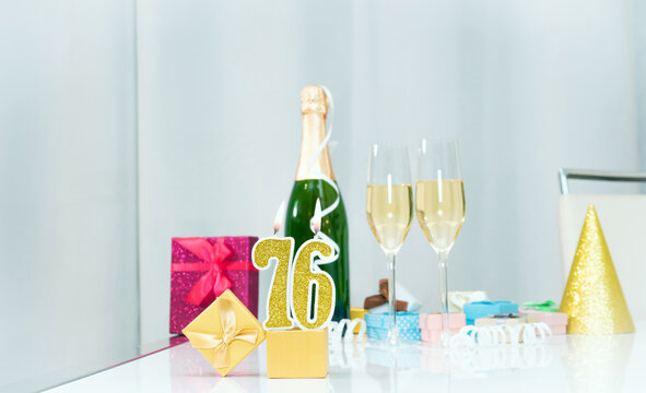 Date of birth with number  76. Festive Champagne in glasses with gift boxes, anniversary postcard. Happy birthday golden candles.
