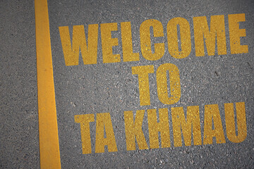 asphalt road with text welcome to Ta Khmau near yellow line.