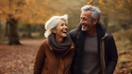 Fototapeta premium elderly senior couple walking together in autumnal forest. retirement enjoying