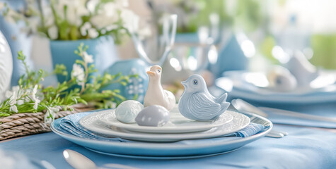 Festive Easter table setting with eggs, bird and spring flowers on a blue linen background. Festive...