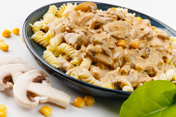 Pasta with cream sauce, mushrooms and corn on a white background