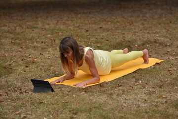 A middle-aged woman is doing yoga in the park