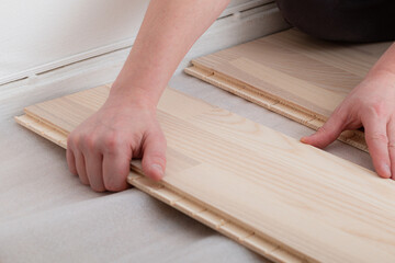 Professional worker installing new parquet flooring indoors, closeup