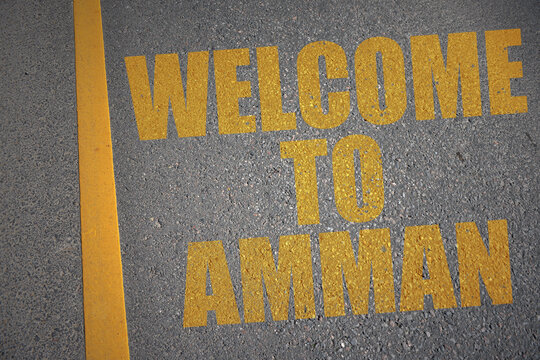 asphalt road with text welcome to Amman near yellow line.