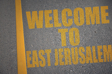 asphalt road with text welcome to East Jerusalem near yellow line.