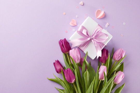 Best gifts for important people: explore the world of gifts on March 8th. Top view photo of gift box, tulips bouquet, hearts, confetti on lilac background with advert area