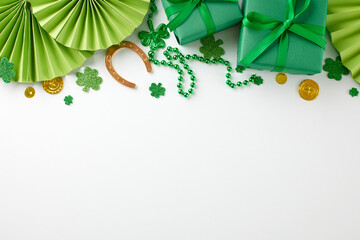 Green gifting galore: perfect presents for St. Patrick's. Top view photo of gift boxes, folding fans, trefoils, coins, beads, horseshoe on white background with advert space