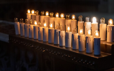 Votive candles lit in dark church.