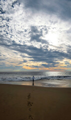 Young man on the beach looking at the sunset, reflecting, space for text
