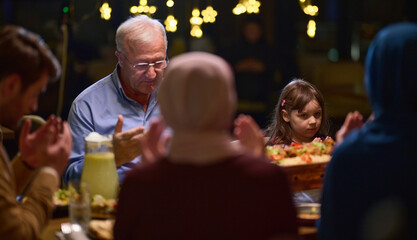 In a modern restaurant setting, a European Islamic family comes together for iftar during Ramadan, engaging in prayer before the meal, uniting tradition and contemporary practices in a celebration of