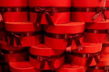 Closeup of gift boxes tied with ribbons, illuminated with warm red light. Stack of presents...