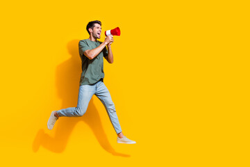 Full length photo of carefree excited guy wear khaki t-shirt jumping high screaming toa empty space...