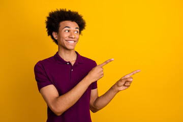 Photo of positive nice man wear trendy violet clothes two arms presents empty space introduces benefit isolated on yellow color background
