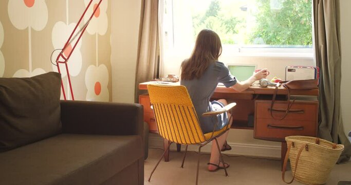 Laptop, coffee and remote work with woman in living room of home, working on startup project from back. Computer, small business and research with freelance employee in apartment for start of career