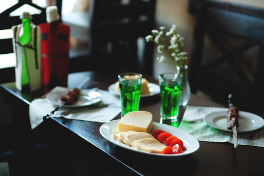 fresh Georgian meal with shashlik kebab with beef or lamb meat, tomato with cheese and green tarragon drink