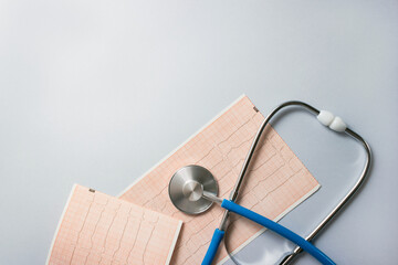 Blue stethoscope and electrocardiogram on gray background. Healthcare concept in 2025. Selective focus, copy space