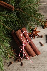 Different spices and fir branches on wooden table, flat lay