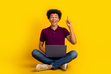 Photo of funny cheerful glad crazy clever man sitting floor finger up great solution decision isolated on yellow color background