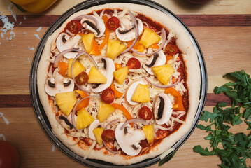 Unbaked homemade pizza with vegetables and pineapple