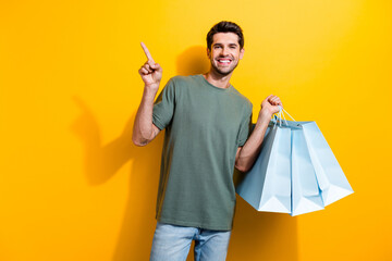 Portrait of toothy beaming guy with bristle hold shopping bags indicating at discount empty space...