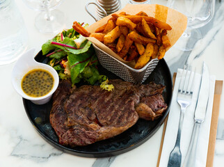 Juicy beef entrecote served with French fries, fresh greens salad and piquant lemon mustard sauce...