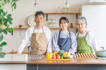 キッチンで料理する高齢者夫婦と若い日本人（家事代行・介護）
