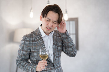 室内でグラスを持ち悩む日本人男性