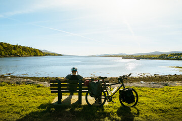 Cyclist enjoy panoramic view on break time by atlantic coast beach on bicycle touring around Ireland