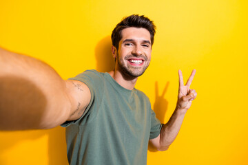 Portrait of cheerful positive guy with bristle wear stylish t-shirt make selfie show v-sign...