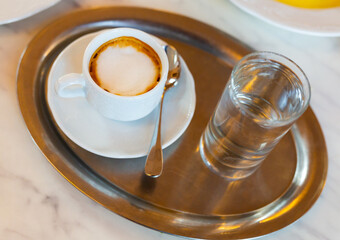 Cup of hot coffee served with glass of clean water for breakfast