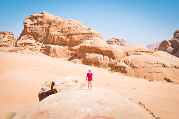 Girl tourist stand on famous arch bridge in wadi rum desert pose and enjoy panoramic view of scenic rock formations