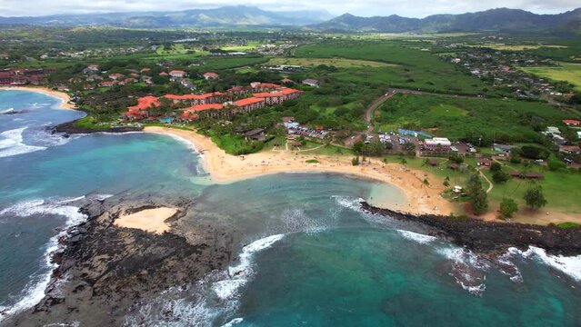 4K drone footage of Poipu beach in Kauai, HI with the bluest water and warm sandy beach.