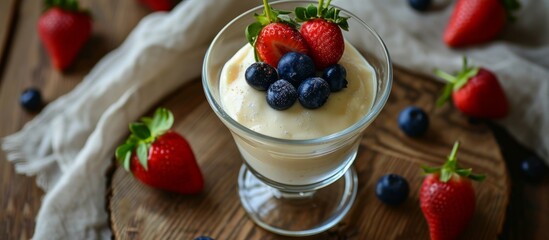 A fruit-infused glass of yogurt topped with strawberries and blueberries, a delicious and refreshing dish.