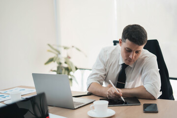 Young business man working in office with laptop and papers on desk, Businessman working on a laptop computer in the office, Businessman working in a new office