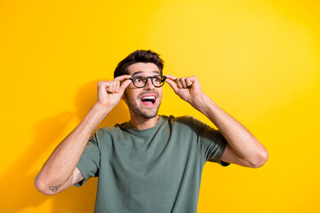 Photo of excited funky guy wear khaki t-shirt arms hands spectacles looking empty space isolated...