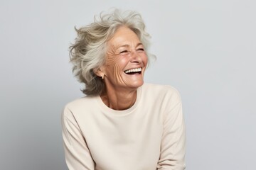 Happy senior woman laughing and looking at camera, isolated on grey background