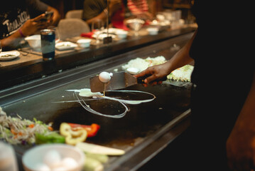 In Teppanyaki, Japanese cuisine style,c hef might juggle utensils, flip a shrimp tail into their shirt pocket, catch an egg in their hat, toss an egg up in the air and split it with a spatula