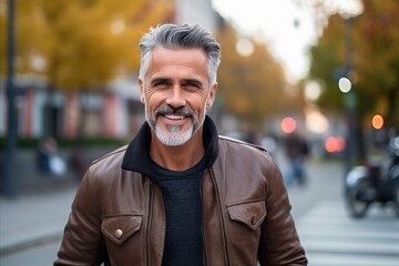 Portrait of a handsome mature man with grey hair and beard in the city