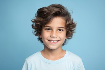Portrait of a smiling little boy with curly hair on blue background