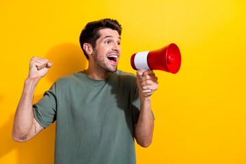 Portrait of handsome guy with stubble wear stylish t-shirt scream in loudspeaker look empty space isolated on yellow color background